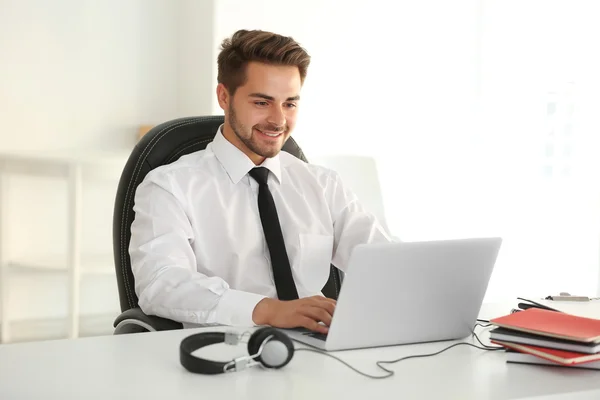 Beau jeune homme travaillant sur ordinateur portable au bureau — Photo