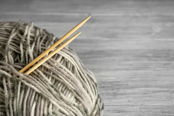 Ball of multicolored knitting yarn and needles on grey wooden background — Stock Photo, Image