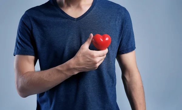 Joven con corazón rojo sobre fondo gris —  Fotos de Stock