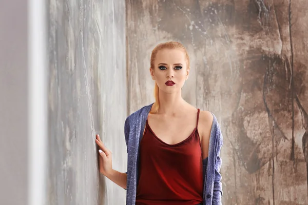 Mooie jonge blonde vrouw in casual kleding tegen grunge achtergrond — Stockfoto