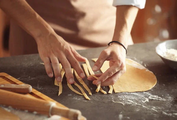 Чоловік готує макарони на кухонному столі, крупним планом — стокове фото