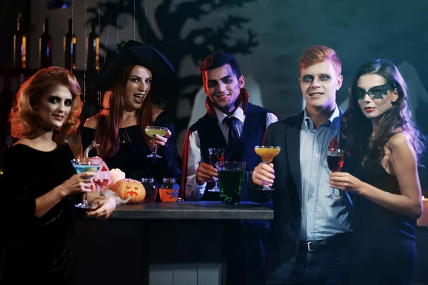 Jeunes en costumes différents buvant des cocktails à la fête d'Halloween — Photo