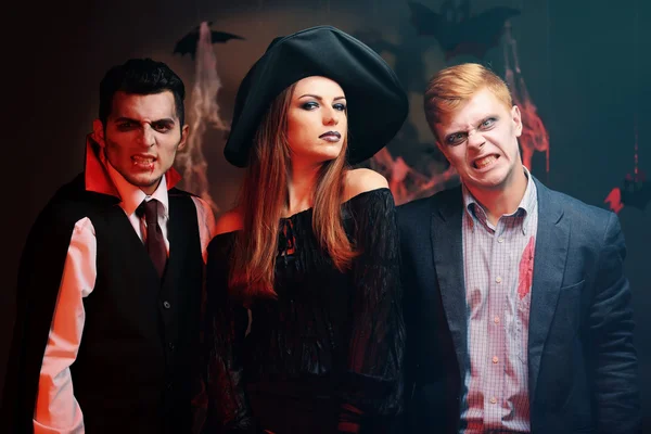 Young people dressed in costumes for Halloween party, on dark background — Stock fotografie