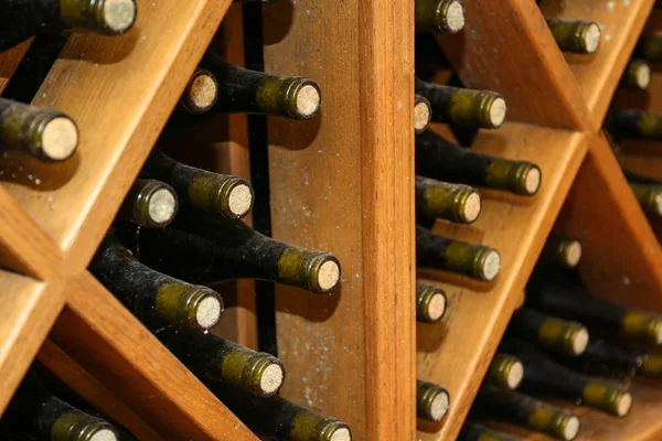 Bottles with wine on wooden shelves in cellar — Stock Photo, Image