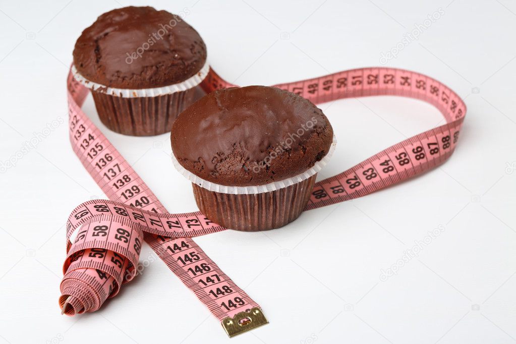 Tasty chocolate muffins with measuring tape on white table