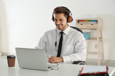 Yakışıklı adam ofisinde kulaklık ile müzik dinlemek