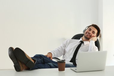 Kulaklık ile müzik dinlemek ve ayakları masaya koyarak yakışıklı adam