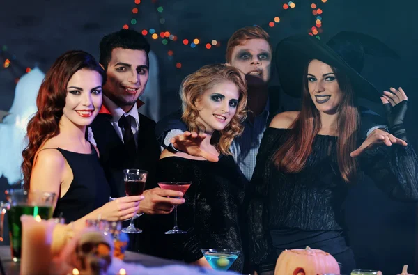 Молодые люди в костюмах пьют коктейли на вечеринке в честь Хэллоуина — стоковое фото