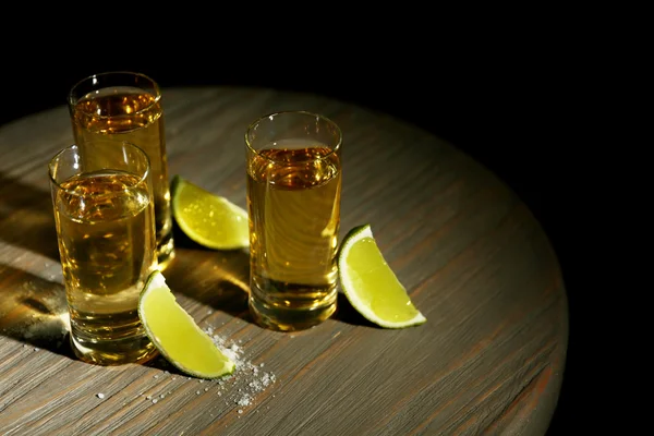 Copos de tequila de ouro com limão e sal na mesa de madeira — Fotografia de Stock