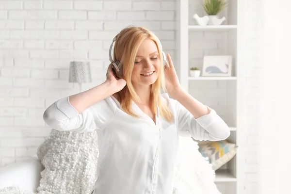 Mujer joven con auriculares escuchando música y divirtiéndose en una sala de luz — Foto de Stock