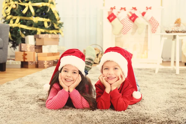 Schattige kleine kinderen in Santa hoeden thuis — Stockfoto