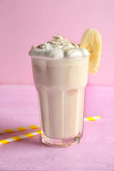 Delicioso milkshake com banana no fundo rosa — Fotografia de Stock