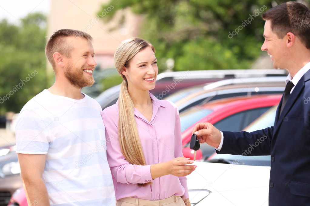 Young couple buying car at dealership center