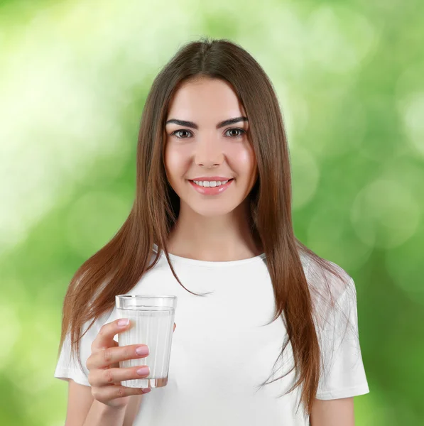Young woman with glass of milk on green blurred background. — Stock Photo, Image