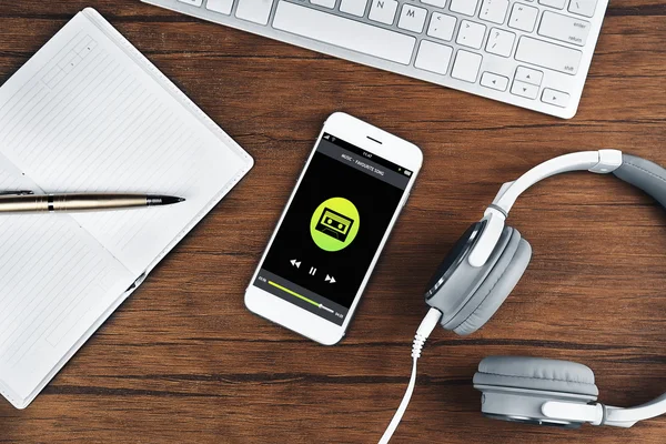 Smartphone and earphones on wooden table, closeup. Music player interface on screen.