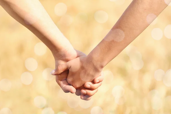 Jong koppel hand in hand samen op vervaagd de achtergrond van een veld — Stockfoto