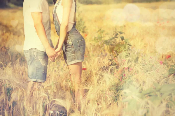 Молодая пара, держащаяся за руки на поле — стоковое фото