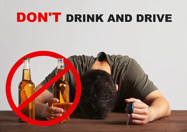 Пьяный молодой человек с ключом от машины и бутылкой пива в баре. Text DON 'T DrINK AND DRIVE on background . — стоковое фото