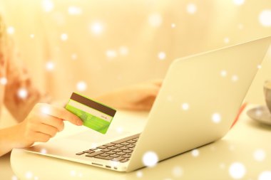 Kredi kartı ve dizüstü bilgisayar, closeup ile eller. Karlı etkisi, online Noel kavramı alışveriş.