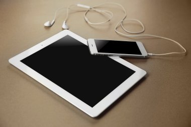 Tablet, akıllı telefon ve kulaklık bej renkli arka plan üzerinde