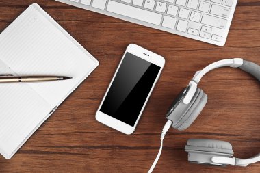 Dizüstü bilgisayar, kulaklık ve bir tablo üzerinde cep telefonu