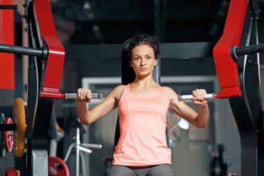 Modern spor salonunda eğitim gören genç bir kadın.