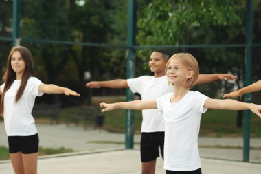 Öğrenciler okul bahçesinde üzerinde fiziksel egzersizleri yapıyor