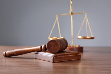 Ahşap masa ve gri arka plan üzerinde hakimin tokmak ve adalet ölçekler