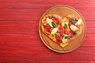 Ahşap arka plan üzerinde kalp şeklinde pizzayla plaka