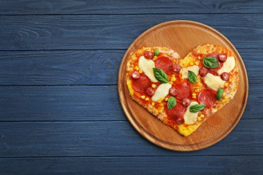 Ahşap arka plan üzerinde kalp şeklinde pizzayla plaka