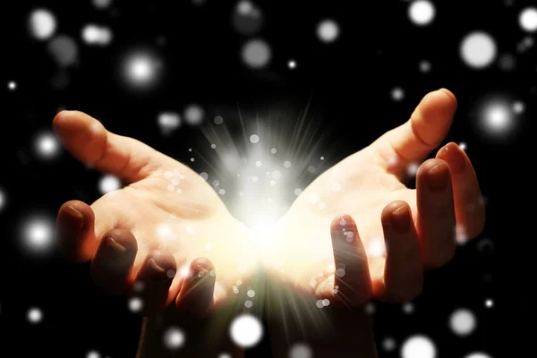 Female hands holding light in dark, closeup. Snowy effect, Christmas miracle concept. — Stock Photo, Image