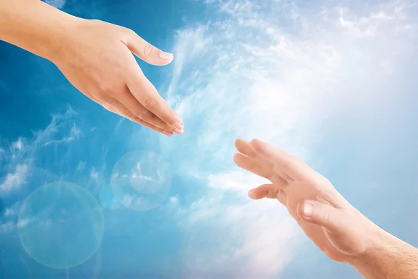 Mãos femininas e masculinas alcançando um ao outro no fundo do céu. Conceito de ajuda e cuidado . — Fotografia de Stock