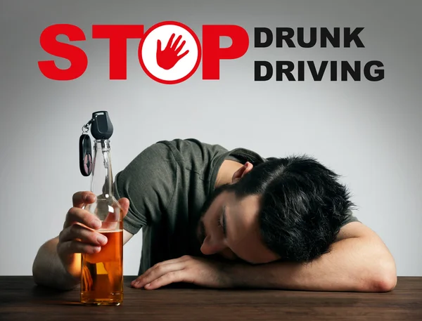 Dronken jongeman met auto sleutel en bier fles op balk. Tekst stoppen Drunk Driving op achtergrond. — Stockfoto