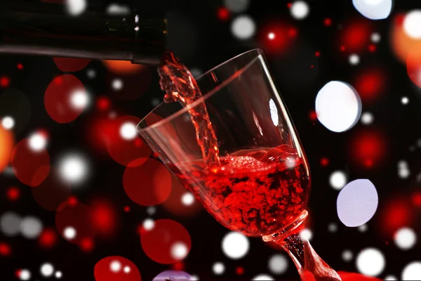 Verter vino tinto en una copa sobre fondo bokeh, de cerca. Concepto de celebración de Navidad . — Foto de Stock