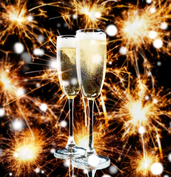 Glasses of champagne on blurred sparkler lights background. Snowy effect, Christmas celebration concept. — Stock Photo, Image