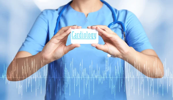 Cardioloog holding visitekaartje met woord cardiologie. Hart care concept. — Stockfoto