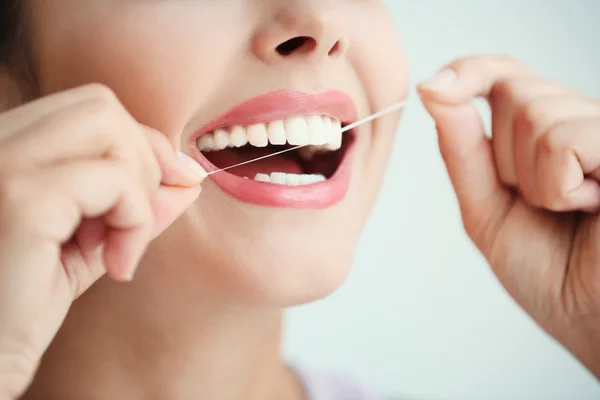 Młoda kobieta czyszczenia zębów z nici dentystycznych, zbliżenie — Zdjęcie stockowe