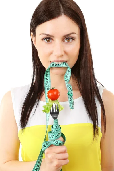 Portret van een jonge vrouw met groenten op vork en meetlint geïsoleerd op wit — Stockfoto