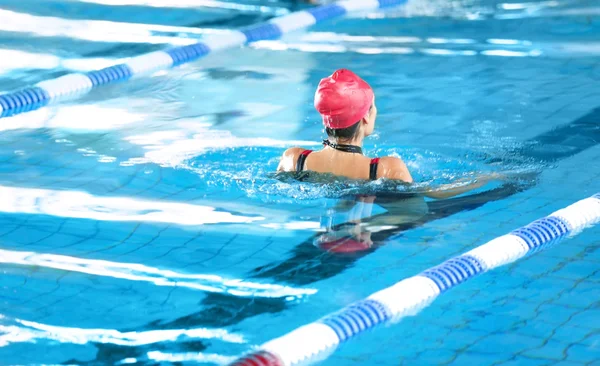 Jente som svømmer i basseng – stockfoto