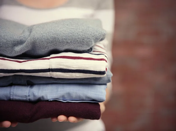 Woman holding pile of clothes, closeup — Stock Photo, Image