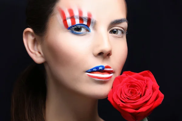 Dívka s Usa make-up a rudá růže na černém pozadí — Stock fotografie