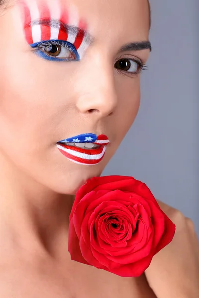 Девушка с американским макияжем и красной розой на сером фоне — стоковое фото