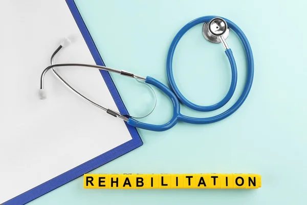 Medical stethoscope and word rehabilitation on blue background — Stock Photo, Image