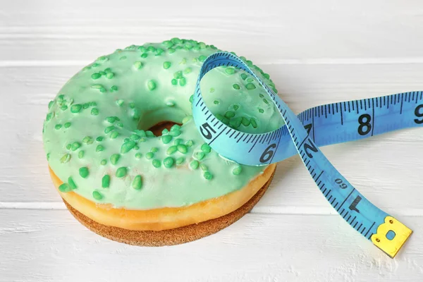 Delicious doughnut and measuring tape — Stock Photo, Image