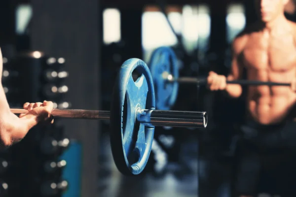 Homem atlético treinando com barbell no ginásio — Fotografia de Stock