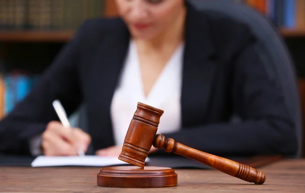 Bruin van de hamer op de houten tafel en vrouwelijke advocaat op de achtergrond, close-up — Stockfoto