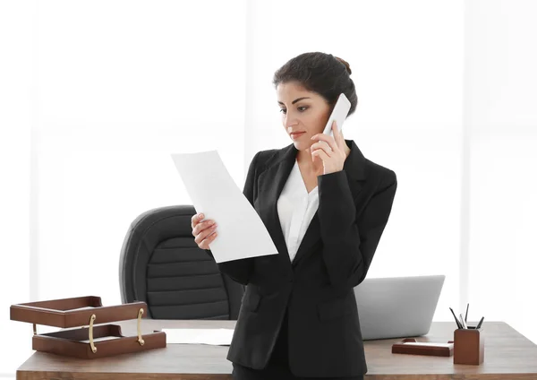 Erfolgreiche reife Geschäftsfrau mit Handy und Dokumenten im Büro — Stockfoto