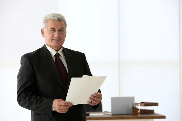 Retrato de exitoso hombre de negocios maduro con papeles en la oficina —  Fotos de Stock