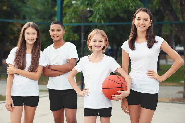 Teens with ball for basketball on school yard