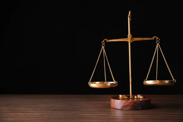 Чешуя правосудия на деревянном столе и черном фоне — стоковое фото